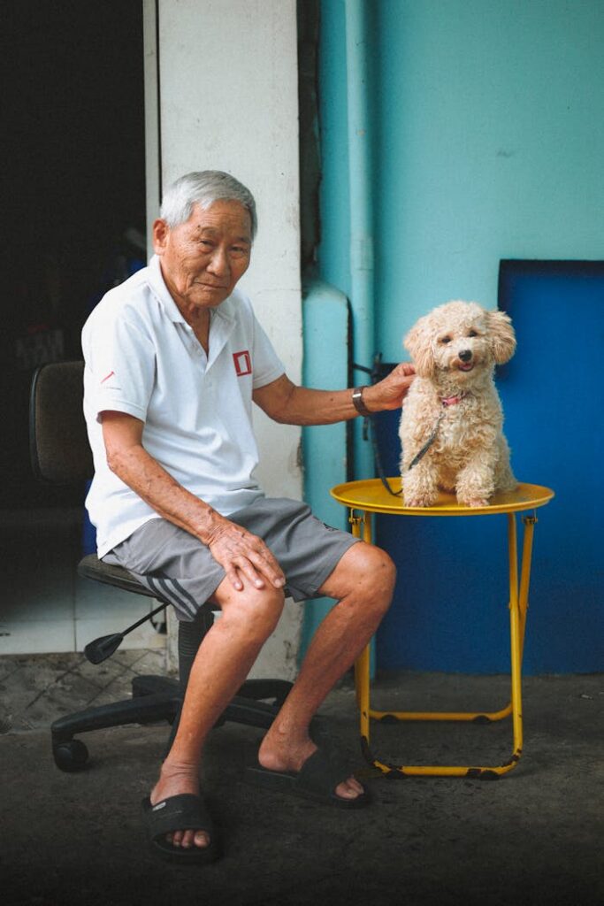 Portrait of an elderly man sitting with his poodle in Ho Chi Minh City.