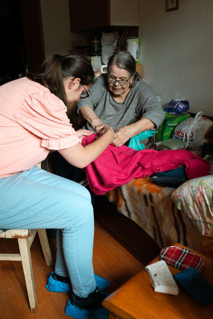 our-journey-01 A caregiver helps a senior woman with sewing indoors in Prague.