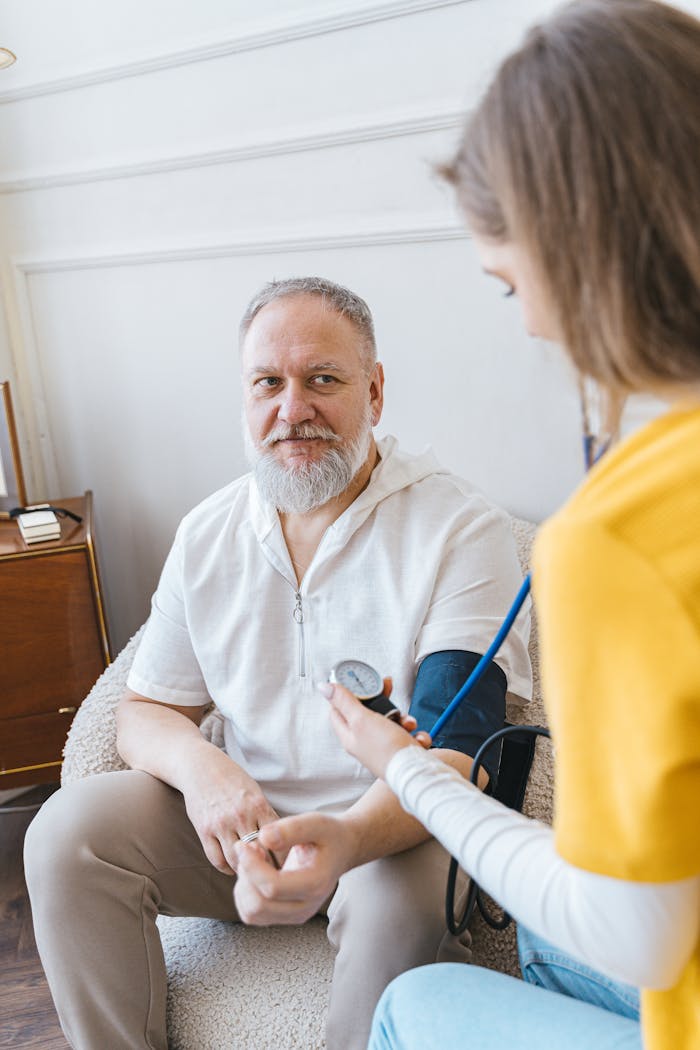 services-03 A healthcare worker takes the blood pressure of an elderly man using a monitor in a cozy indoor setting.