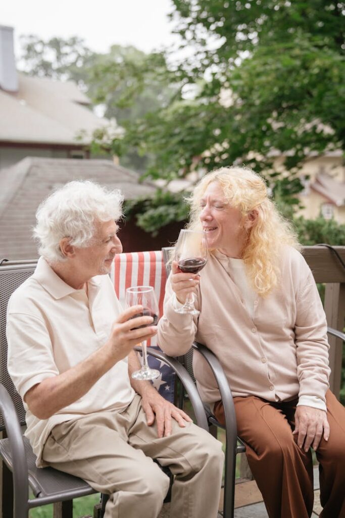 Smiling senior couple enjoying a wine toast outdoors, celebrating life together.
